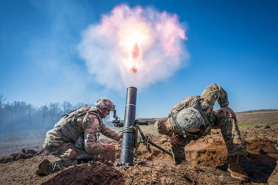 Soldiers firing a mortar in the field